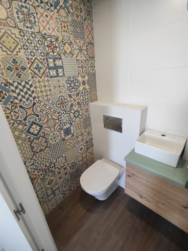 Baño moderno con azulejos decorativos y lavabo sobre un mueble de madera.