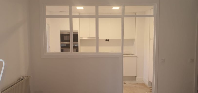 Cocina moderna minimalista con muebles blancos y amplias ventanas.