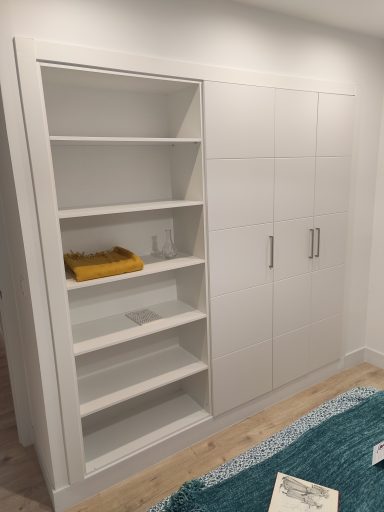 Mueble blanco con estanterías abiertas y armario con puertas. Fondo neutro.